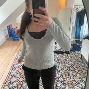 Grå v-ringad tröja - Säljer en stilren grå v-ringad tröja med långa ärmar och ribbade detaljer vid ärmslut och nederkant.