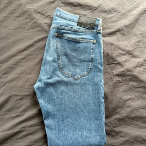 Blå jeans från Lee - Snygga blå jeans från Lee med klassisk design. De har en normal passform och är tillverkade i slitstarkt denim. Perfekta för en avslappnad stil. Nypris 1199kr