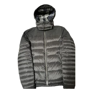 Svart dunjacka med huva - Snygg svart dunjacka med dragkedja och huva. Perfekt för kyliga dagar med sin quiltade design som håller värmen. Jackan har en stilren look och passar bra till olika outfits.