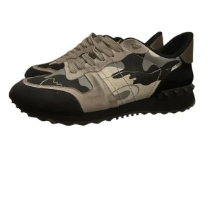 Camouflage sneakers från Valentino - Snygga sneakers från Valentino med ett coolt camouflage-mönster i svart, grått och beige. Väldigt bra skick men är bara smutsiga, rengör de givetvis vid försäljning. Vad som medföljer är skor: dustbag och låda (ganska dåligt skick). Har även digitalt kvitto 