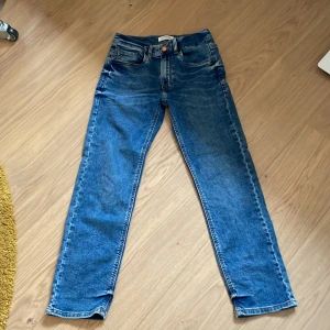 Blå jeans från Lindex - Säljer ett par klassiska blå jeans från Lindex. De har en rak passform med fem fickor och knappgylf. Jeansen är i Slim fit/Staffan. Storlek 140/9-10Y. Priset är inte hugget i sten, skriv gärna i DM om du vill ha fler bilder. 
