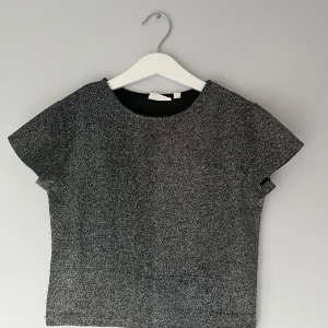 Silver glittrig T-shirt Kappahl - Silver glittrig T-shirt från Kappahl som passar upp till xs som en kroppad tröja