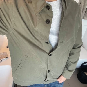 Olivgrön jacka/overshirt från Zara - Säljer en stilren olivgrön jacka från Zara. Jackan har en klassisk krage och knäppning med svarta knappar. Perfekt för en avslappnad look. 🧥