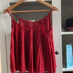 Röd leopardmönstrad linnetopp - Snygg röd linnetopp med leopardmönster och tunna axelband. Perfekt för en djärv och trendig look. Passar bra till både jeans och kjol.
