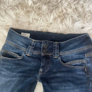 Lowwaisted mörkblå bootcut jeans - Sjukt snygga mörkblå bootcut jeans från Pepe Jeans med en straight passform, liknar flared jeans mycket då de är lite större nertill. De har jättesnygga detaljer vid midjan och på bakfickorna. Jag har aldrig använt byxorna då de inte rkt passar, därför i nyskick! De är i storlek W27 och L32 och är  stretchiga. Köpta för ca 800 kr på Zalando. Det är bara att skriva om frågor kring mått o bilder osv🥰🥰