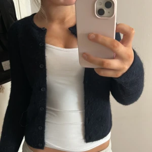 Mörkblå kofta - Säljer en mysig mörkblå kofta med knappar framtill. Perfekt för kyligare dagar och lätt att matcha med olika outfits. Koftan har långa ärmar och en klassisk design.