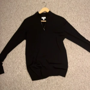 Svart tröja med dragkedja från Sunspel - Säljer en stilren svart cashmere half zip från Sunspel. Tröjan har långa ärmar och är tillverkad i Portugal. Perfekt för en elegant och på samma sätt chill look.