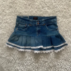 Jeanskjol med spetsdetaljer - En lågmidjad jeanskjol omsydd från ett par jeans. Midjemått tvärsöver - 39cm Längd - 32 cm