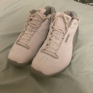 Vita sneakers från AND1 - Snygga vita basketskor från AND1 med grå detaljer. De är vintage och i väldigt bra skick ändå även om de varit använda sen länge tillbaka. Skorna har en stilren design med snörning och perforerade sidor för extra ventilation. Perfekta för en sportig look. Kan såklart användas som vanliga skor också. Pris kan diskuteras.