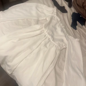 Vit klänning från Shein - Säljer en elegant vit klänning från Shein med smockdetaljer i midjan. Klänningen har långa ärmar och en luftig passform. Perfekt för en stilren look. 🌟
