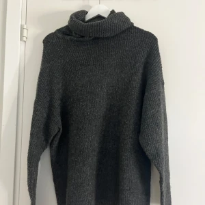 Mörkgrå stickad polotröja - En mörkgrå stickad tröja med polo nacke, skönt material i storlek XS! Väldigt stor i storleken och passar nog alla storlekar. 