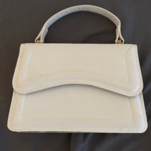 Handväska  - Vit söt handväska  Stilren och enkel, perfekt för att bära i handen. Ingen kedja eller axelrem, bara en söt liten väska som passar till både vardag och fest!. För 30kr 