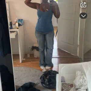 Blå bootcut jeans med slitningar - Säljer ett par blå bootcut jeans dom är lite slitna vid benen. Jeansen har en klassisk femficksdesign och en liten dragkedjeficka bak. Perfekta för en avslappnad och trendig look.