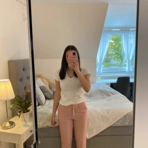 Rosa kostymbyxor från KappAhl - Säljer ett par ljusrosa kostymbyxor från KappAhl i storlek 36. Byxorna har normal passform, hällor för bälte och stängs med dragkedja och knapp. Perfekta för en stilren och trendig look.