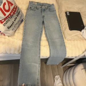 Ljusblå Levis 501 jeans - Säljer ett par klassiska ljusblå Levis 501 jeans med raka ben och knäppning med knappar. Jeansen har fem fickor och den ikoniska Levis-lappen bak. Perfekta för en avslappnad och tidlös stil.
