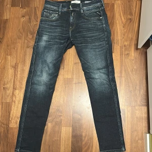 Replay Anbass slim fit jeans - Snygga mörkblå Replay Anbass jeans med slim fit. Klassisk femficksmodell med snygga slitningar och kontrastsömmar. Märkespatch bak i midjan och diskreta detaljer. Perfekta för dig som gillar en smalare passform och stilren look. W29 L30
