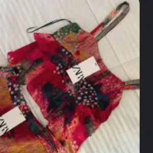 Färgglad croppad linnetopp från Zara - Säljer en färgglad croppad linnetopp från Zara med abstrakt mönster i rött, grönt, orange och svart. Tunt material med smala axelband och lös passform. Perfekt för sommardagar och festivaler!