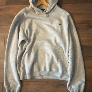 Grå hoodie från Nike | strl S - Grå hoodie från Nike i oversized modell i storlek Small. Tröjan har en liten fläck på framsida mage