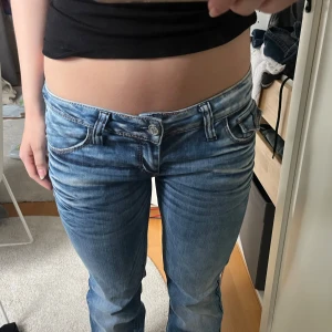 Lågmidjade bootcut jeans - Säljer ett par ljusblå jeans med broderade detaljer på bakfickorna. Jeansen har låg midja och utsvängda ben. Storlek W29/L32 och passar S/36❣️Midjan är 39cm tvärsöver