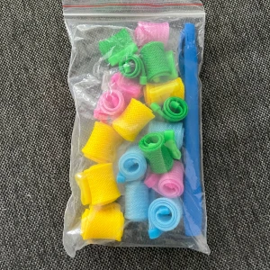 Färgglada hårspolar i plast - Säljer ett set med hårspolar i plast i färgerna gul, grön, rosa och blå. Kommer i en genomskinlig zip-påse tillsammans med ett blått verktyg för att applicera spolarna. Perfekt för att skapa lockar utan värme.