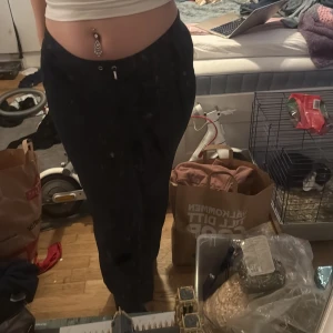 Mörkblå Juicy Couture  - Mysiga svarta Juicy Couture med resår och dragsko i midjan. Byxorna har en loose passform och är tillverkade i ett mjukt, syntetiskt material som känns skönt mot huden. Perfekta för en avslappnad stil. Har litet hål på låret 