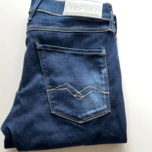 Mörkblå Replay Anbass jeans - Säljer ett par mörkblå Replay Anbass jeans med klassisk femficksdesign och snygga kontrastsömmar. Jeansen har normal passform och är tillverkade i ett stretchigt denimtyg. Perfekta för dig som gillar stilrena och bekväma jeans.