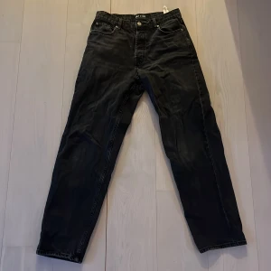 Svarta jeans från ONLY & SONS - Säljer ett par svarta jeans från ONLY & SONS med klassisk femficksdesign och raka ben. Jeansen har normal passform och stängs med dragkedja och knapp. Perfekta till vardags för en stilren look.