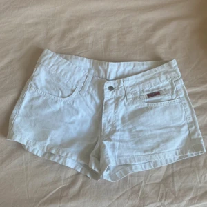 Vita jeansshorts med fickor - Snygga vita jeansshorts med klassisk femficksdesign och knappstängning framtill. Shortsen har bälteshällor och är i en kort modell som passar perfekt till varma dagar.