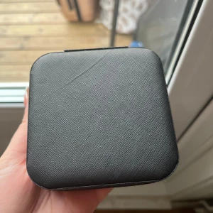 Svart smyckesask med spegel - Praktisk och stilren svart smyckesask med dragkedja och inbyggd spegel. Insidan har flera fack för ringar, örhängen och andra smycken. Perfekt för att organisera dina favoritsmycken hemma eller på resan.