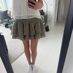 olivgrön Volangkjol  - Supersöt beige kortkjol från LuLu’s med volanger och broderade hål. Kjolen har en luftig och lekfull design med två lager volang och ett snyggt mönster. Perfekt att styla med en enkel topp💓 Köpt för 1399kr 