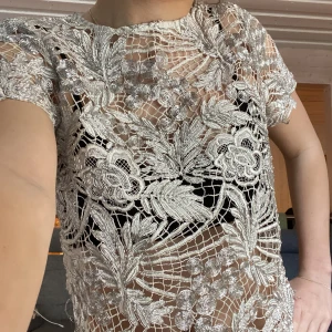 Silvrig spetsblus från Gina Tricot - Säljer en silvrig, kortärmad blus från Gina Tricot i genombruten spets med blommigt mönster. Blusen har rund halsringning och fina detaljer i spetsen som ger ett elegant intryck. Pris kan diskuteras!