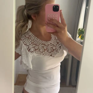 Vit topp med spetsdetaljer - Säljer en söt vit topp med vacker spets upptill och volangärmar 💗är inte helt säker på storlek men passar mig som är s/m