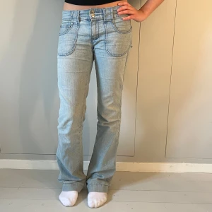 Lågmidjade bootcut jeans - Jättesöta ljusblåa och lågmidjade jeans med bootcut och coola fickor! Passar någon mellan 170-173 skulle jag säga då de är lite långa på mig som är 168, därav är de lite slitna på botten där bak (skriv för bild). Midjemått är 40 cm och innerbenslängd är 80 cm