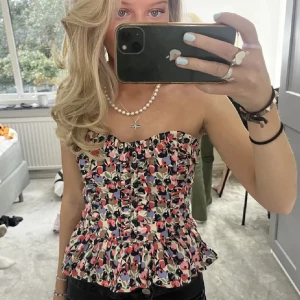 Blommig korsettopp med volang - Säljer denna såå fina korsetttoppen då den tyvär blivit för liten för mig, knappt andvänt så i superbra skick!🩷🙌🏼