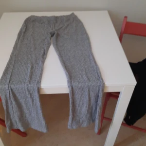 Grå ribbade mjukisbyxor - Gråa mjukisbyxor med ribbad struktur och elastisk midja. Byxorna har en relaxed passform och är perfekta för en avslappnad stil. Mjukt material som känns skönt mot huden.