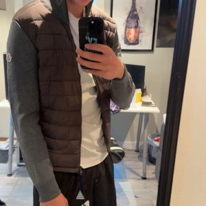 Brun quiltad väst från Moncler med grå ärmar - Säljer nu min moncler cardigan jacka i färgen grå då den var för liten. 