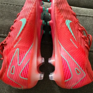 Nike Air Zoom Mercurial Vapor 16 Elite AG-Pro - Nike Air Zoom Mercurial Vapor 16 Elite AG-PRO Mad Energy Röd/Grön. Storlek 44/US10 Använda en vecka men fötterna växte snabbt så fick köpa nya.  Pris 1200kr (Nypris 3399kr). Vid snabbt köp är 1000 lägsta priset. 