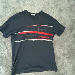 Mörkblå t-shirt från Jacob Cohën - Mörkblå Jacob Cohën T-shirt. Röd och vit på framsidan med Jacob Cohën tryckt över bröstet. Storlek M.