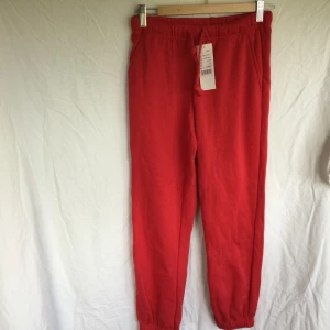 Röda mjukisbyxor från Clique - Säljer ett par röda mjukisbyxor från Clique i storlek XS. Byxorna har resår och snörning i midjan samt muddar vid bensluten. Tillverkade i en mjuk blandning av polyester och bomull, perfekta för en avslappnad stil. Oanvända ! 65% polyester 35% bomull Beninnerlängd: 75 cm. Katter finns i hemmet!