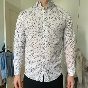 Vit mönstrad skjorta - Säljer en mönstrad långärmad skjorta från Jack & Jones med små blå blommor och växtmönster. Passformen är slim, perfekt för sommaren☀️
