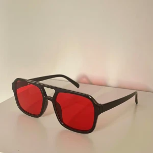Snygga solglasögon med röda glas - Snygga svarta solglasögon med markerad båge och röda, fyrkantiga linser🔥Modellen har en modern och lite oversized känsla, perfekt för dig som vill sticka ut med en cool accessoar😎