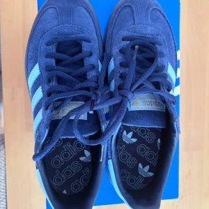 Adidas Spezial sneakers i blå mocka - Säljer ett par Adidas Spezial sneakers i mörkblå mocka med ljusblå ränder och detaljer. Skorna har klassisk Adidas-design med gummisula och snörning. Perfekta för dig som gillar retrostil och streetwear.