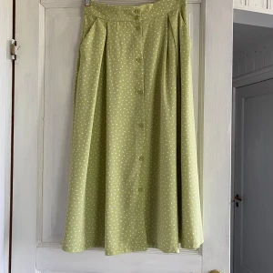 Ljusgrön prickig kjol från Monki - Superfin ljusgrön kjol från Monki med vita prickar och knappar framtill. Två fickor på sidorna. Så fin i sommar! 