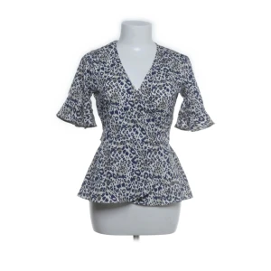 Mönstrad blus från Pigalle - Säljer en jätte fin blus från Pigalle i blått och beige leopardmönster. Blusen har v-ringning, volangdetaljer på ärmarna och knytband i midjan. Pris kan diskuteras💕