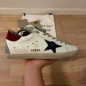 Golden Goose - Ett par sjukt snygga Golden Goose i en unik men sjukt snygg färg!🌟 Vinröd häl och mörkblå stjärna! Storlek 42. Dustbag och 2 andra tillbehör fås med som syns i bilden! Kvitto och äkthetsbevis finns!😊Skick 9/10, grymt skick!