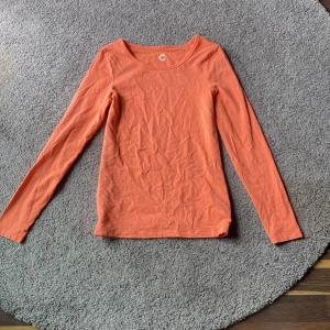 Orange långärmad topp från Cubus - Säljer en enkel och stilren orange långärmad topp från Cubus. Tröjan är i mjuk bomull och har en rund halsringning. Perfekt till sommaren.