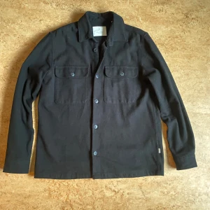 Svart overshirt från Jack & Jones - Stilren svart overshirt från Jack & Jones i mycket mycket bra skick (endast använd ett fåtal gånger). Storlek L och nypris 600 kr.