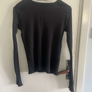 Svart ribbad långärmad tröja från XOXO friends - Säljer en svart långärmad tröja från XOXO friends. Tröjan är ribbad och har en rund halsringning. Perfekt basplagg som är lätt att matcha med olika outfits.