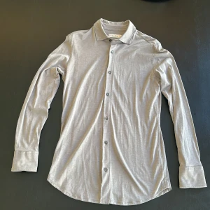 Grå skjorta från Luca Faloni - Snygg grå skjorta från Luca Faloni ”como shirt” i en lyxig blandning av silke och bomull. Perfekt för dig som gillar stilrena och bekväma plagg. Ny pris 3000kr. Säljer pågrund av för liten storlek och ingen bytesrätt längre. Andvänd 0 gånger.