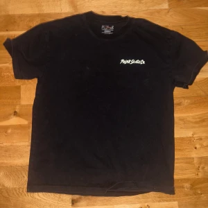 Svart t-shirt från Polar Skate Co med grafiskt tryck - Säljer en svart t-shirt från Polar Skate Co i storlek XS. Framsidan har en liten vit logga på bröstet och baksidan har ett stort färgglatt grafiskt tryck i blått, gult och orange. 